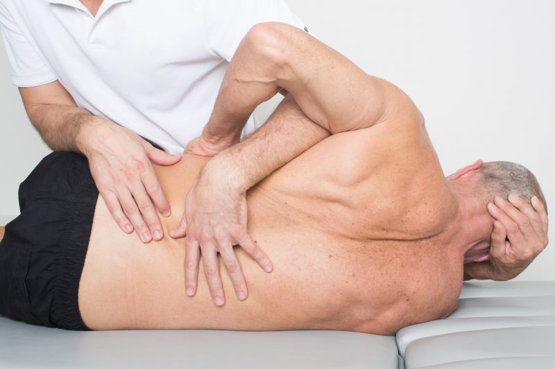 Schmerztherapie am Rücken eines Senioren im Lendenwirbelbereich