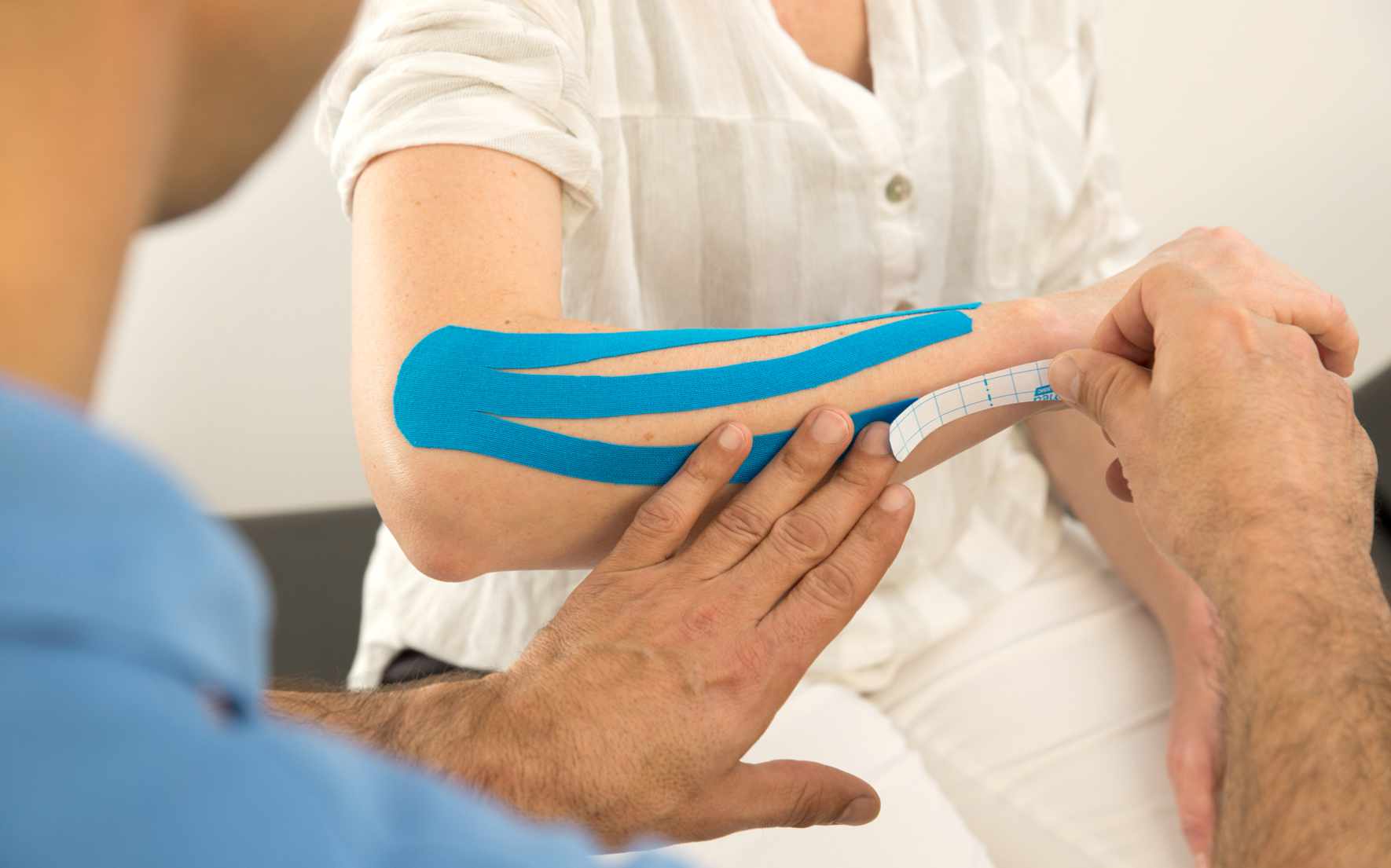 Ankleben eines Tapes am Unterarm eines Patienten