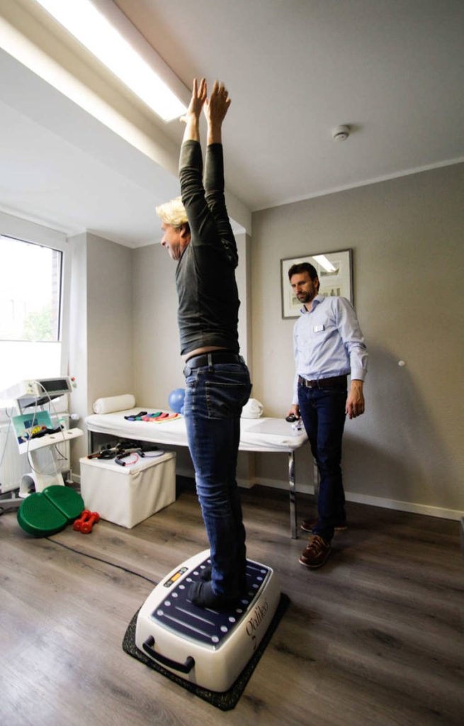 Patientin auf galileo vibrationsplatte streckend unter Anleitung des Therapeuten.